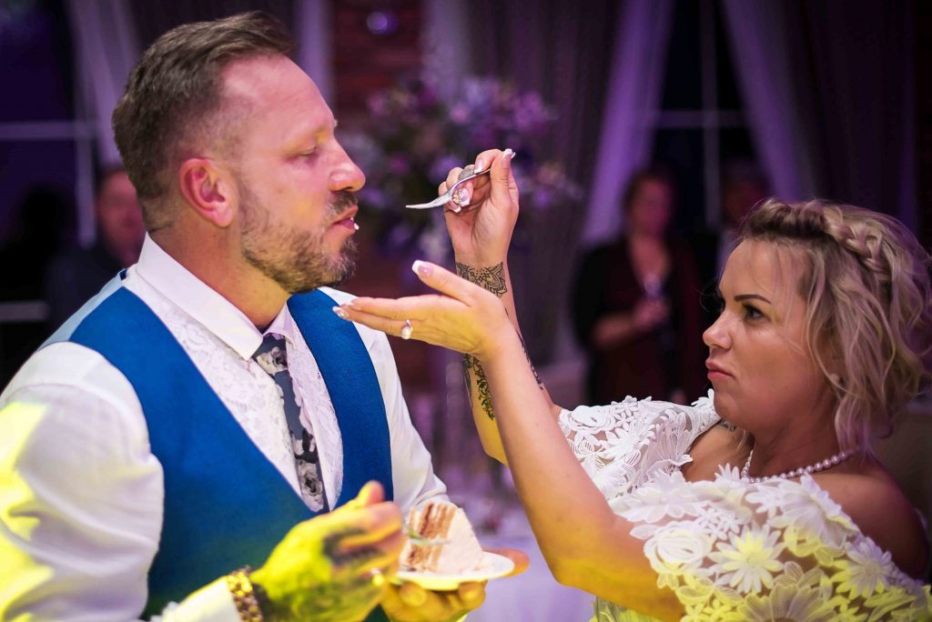 Newlyweds cutting the cake at a rustic barn wedding