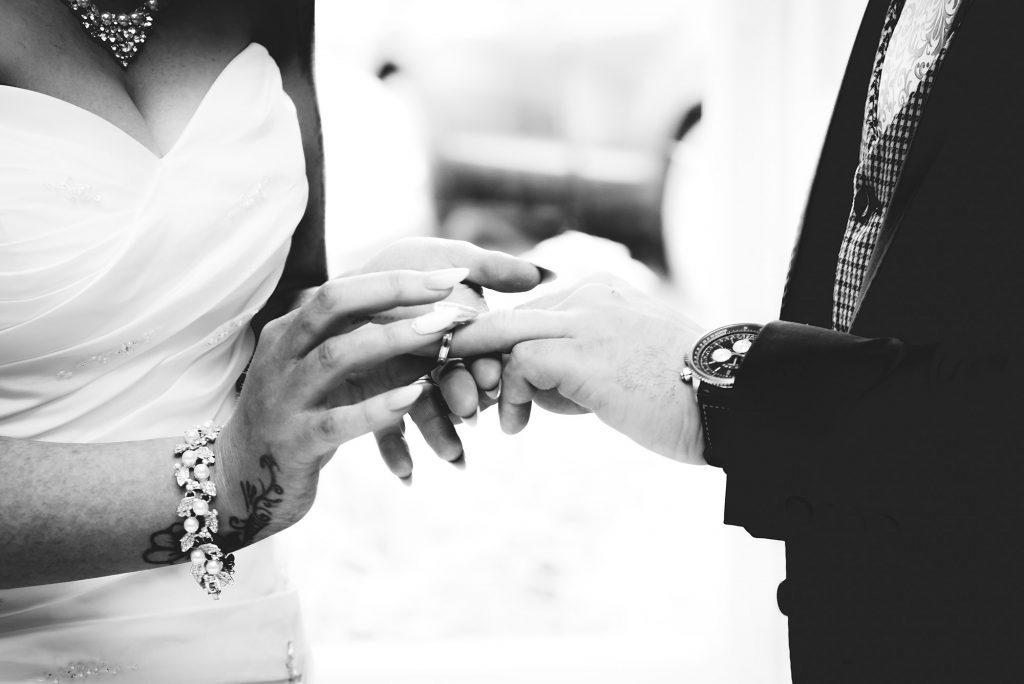 Close-up of wedding rings with intertwined hands.