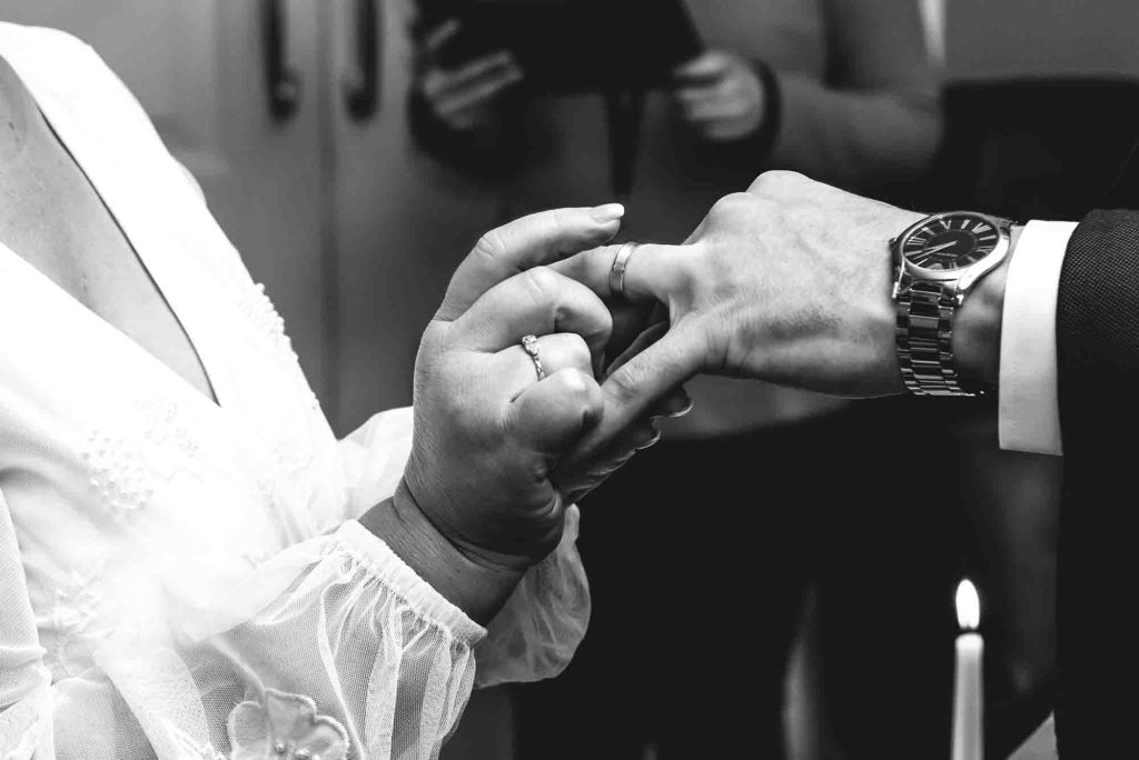 Bride and groom's hands intertwined, showcasing their wedding rings.