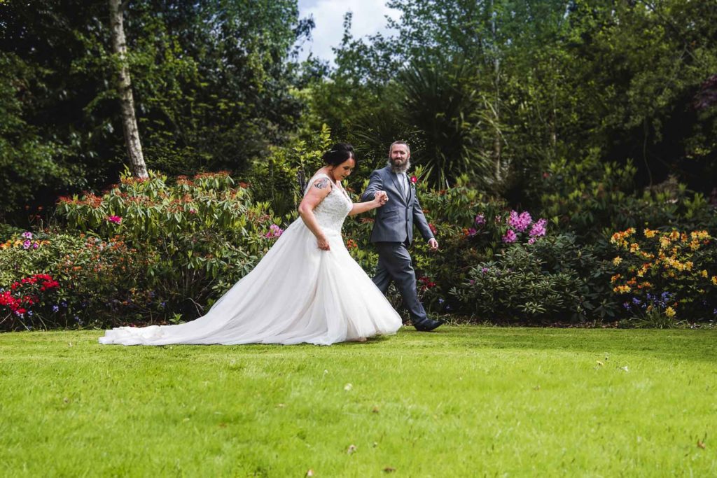 Elegant wedding day stroll – the bride in a flowing gown and groom in a sharp suit. Clonmel
