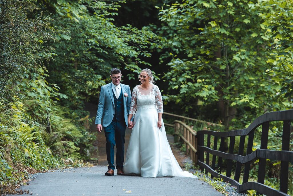 Romantic newlyweds walking hand in hand during golden hour.